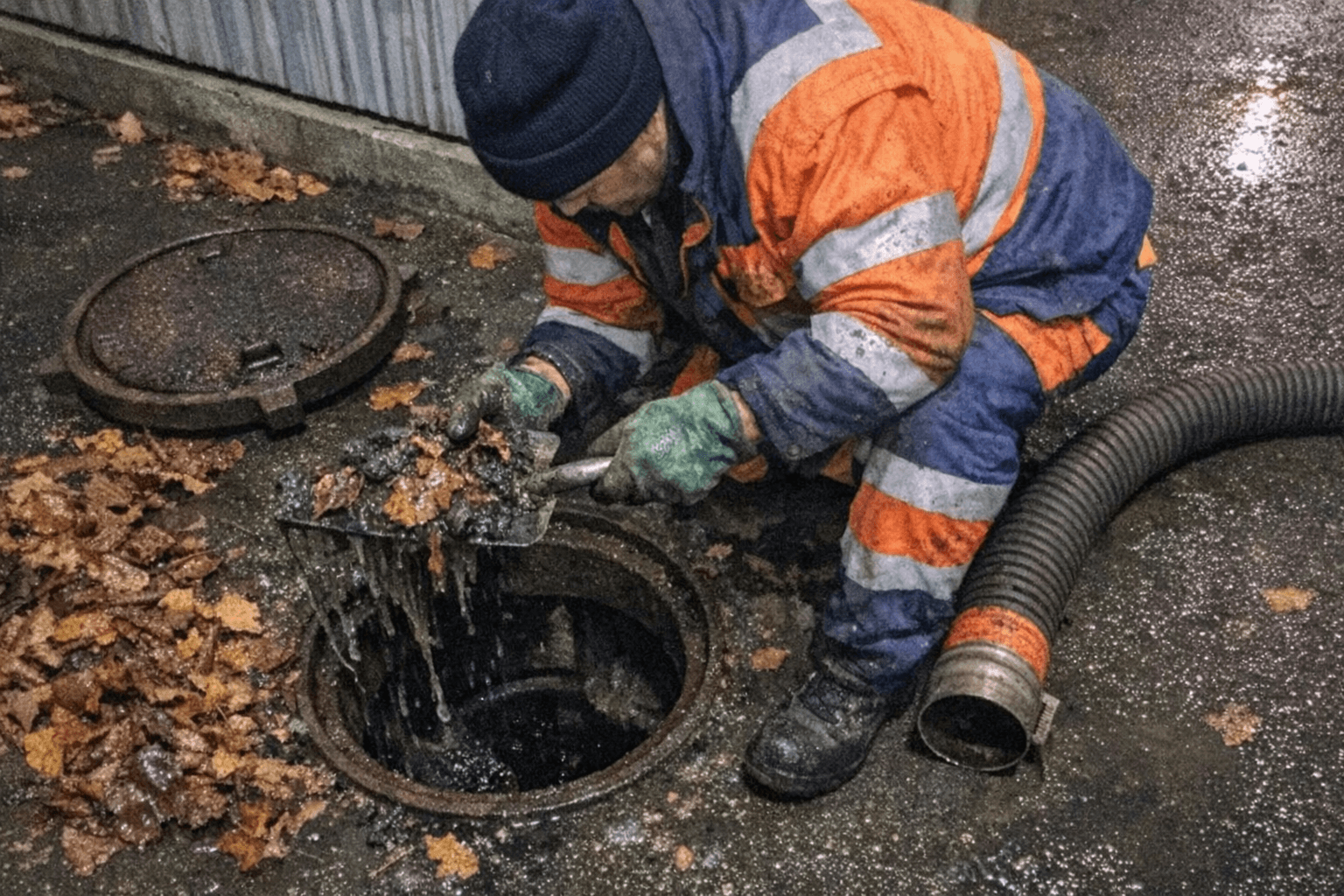 Geöffneter Hofschacht mit entferntem Schlamm neben einem Einsatzfahrzeug